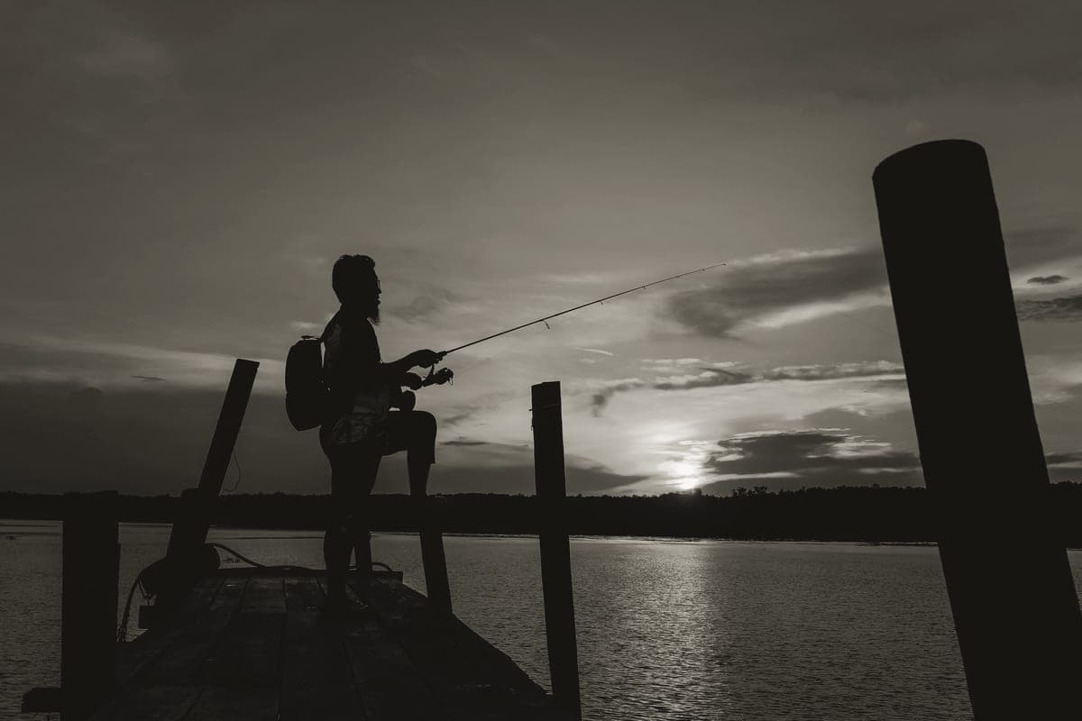 An angler on a wooden dock at sunrise