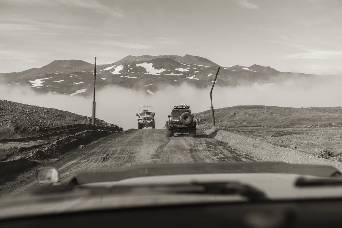 A vehicle on a dirt track running toward distant mountains
